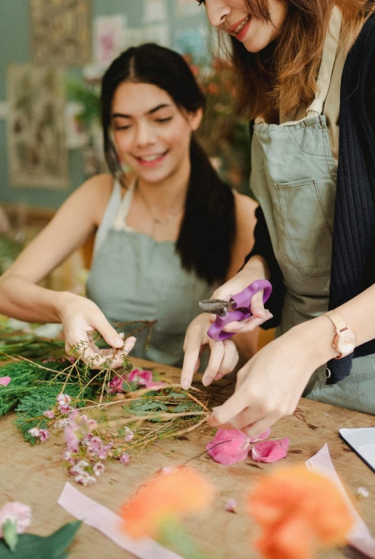 Zwei Kursteilnehmbereiten die Blumen für einen Strauss vor.