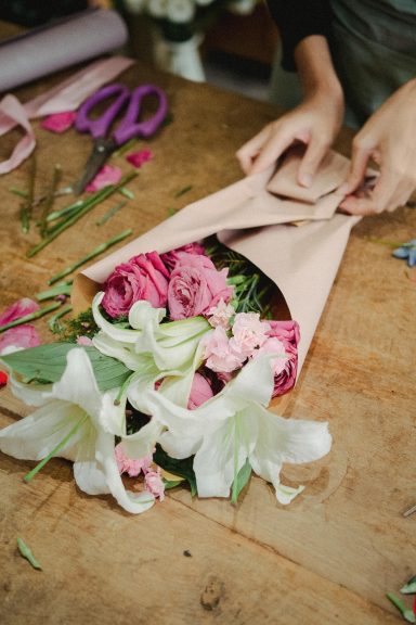 Eleganter Strauß mit burgunderfarbenen und cremefarbenen Rosen in braunem Papier - Floristik Workshop
